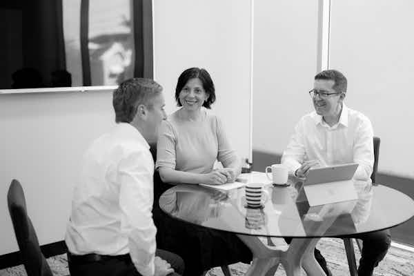 three team members sitting around a table discussing numbers